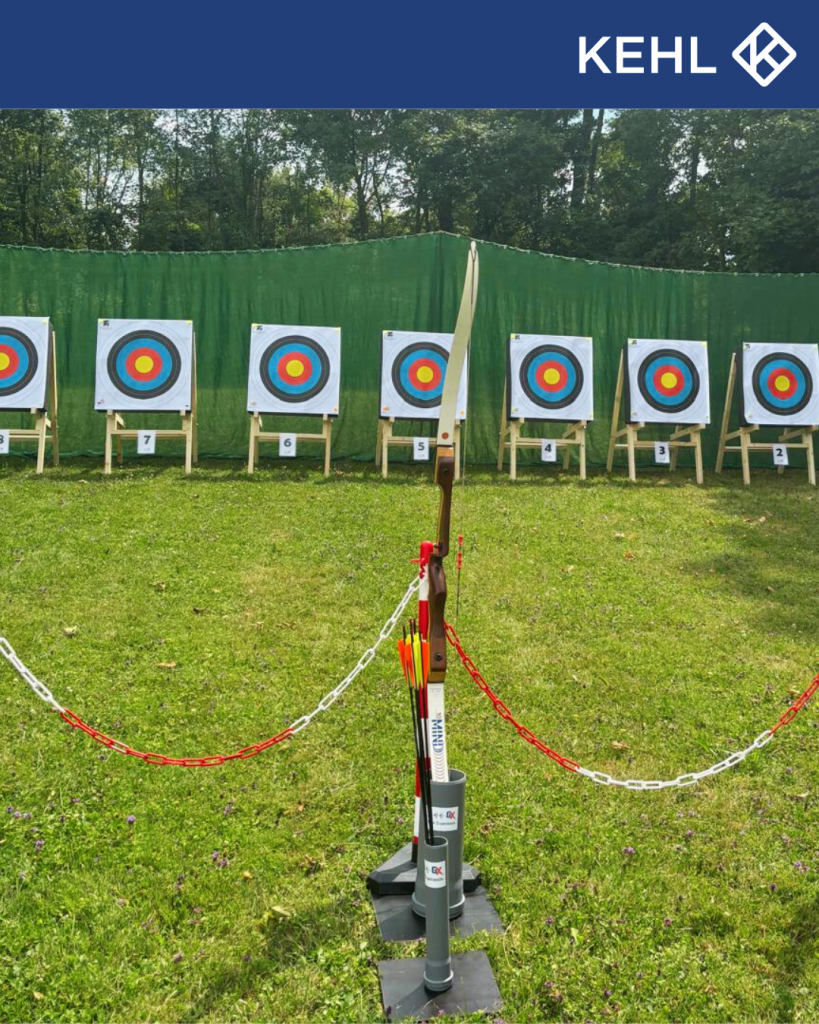 Mehrere Zielscheiben mit Pfeilen und einem Bogen im Vordergrund.